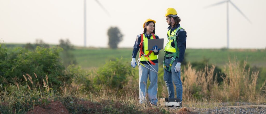 engineer and worker discussing on a wind turbine farm with blueprints